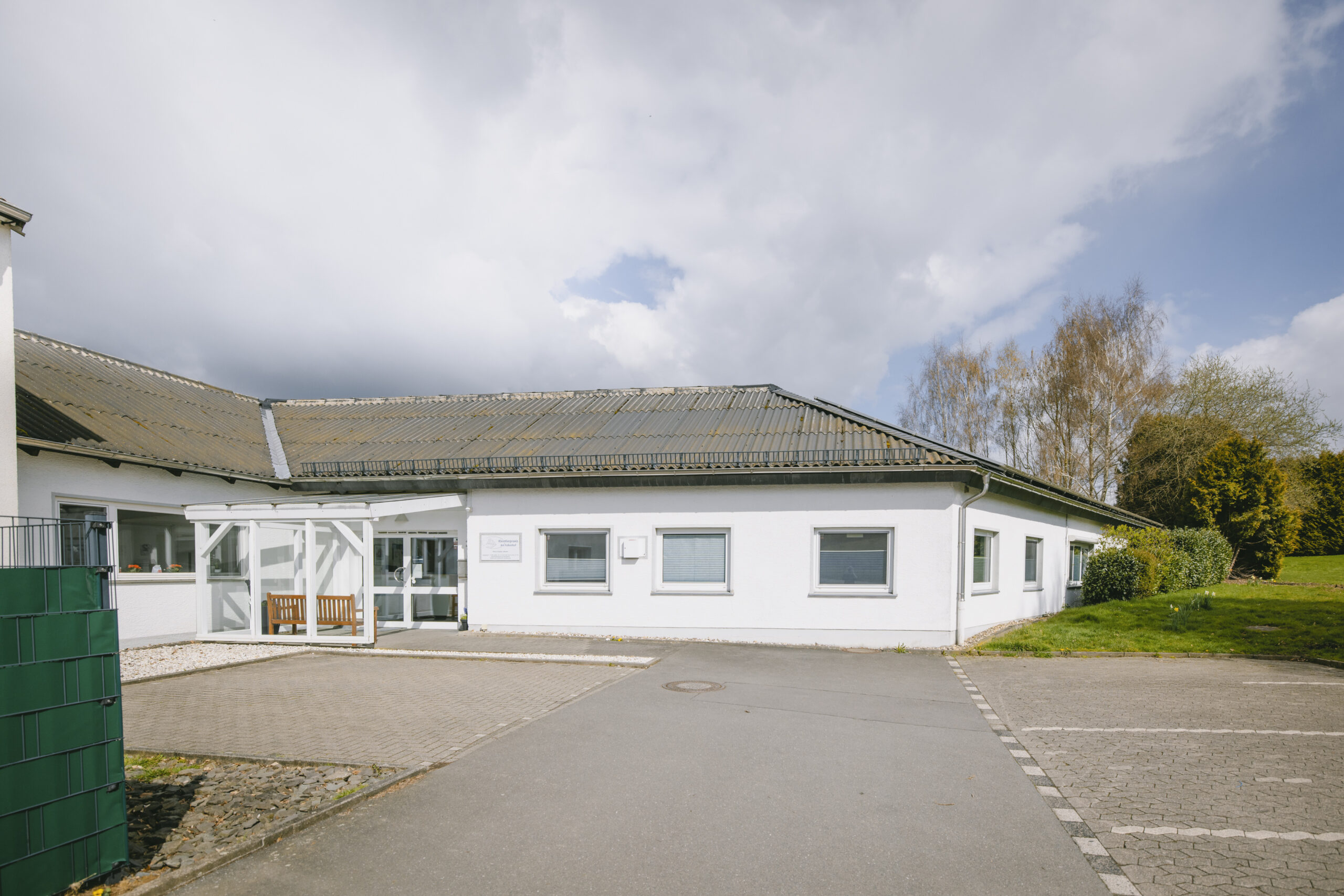 Außenansicht der Tierarztpraxis mit überdachtem Eingang und Parkplatz.